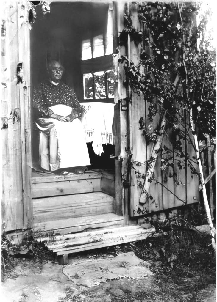 photo of Sofia in the doorway of her home. The doorway has been decorated with birch branches in preparation for Midsommar.